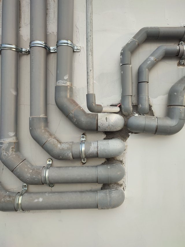 Interconnected pipes and fittings on a wall