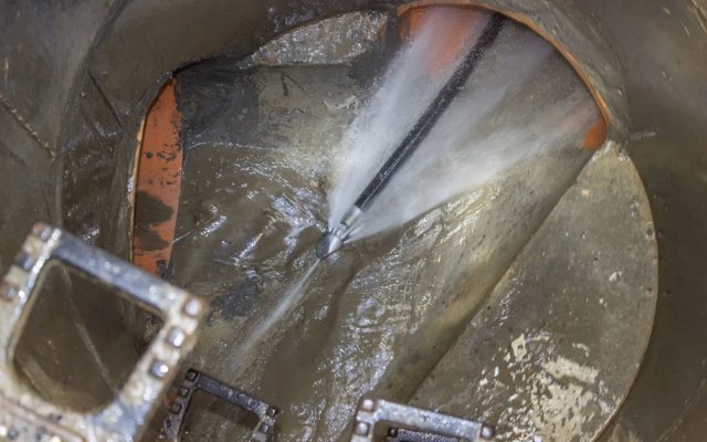 High-pressure water jetting nozzle clearing grease and roots inside a sewer line